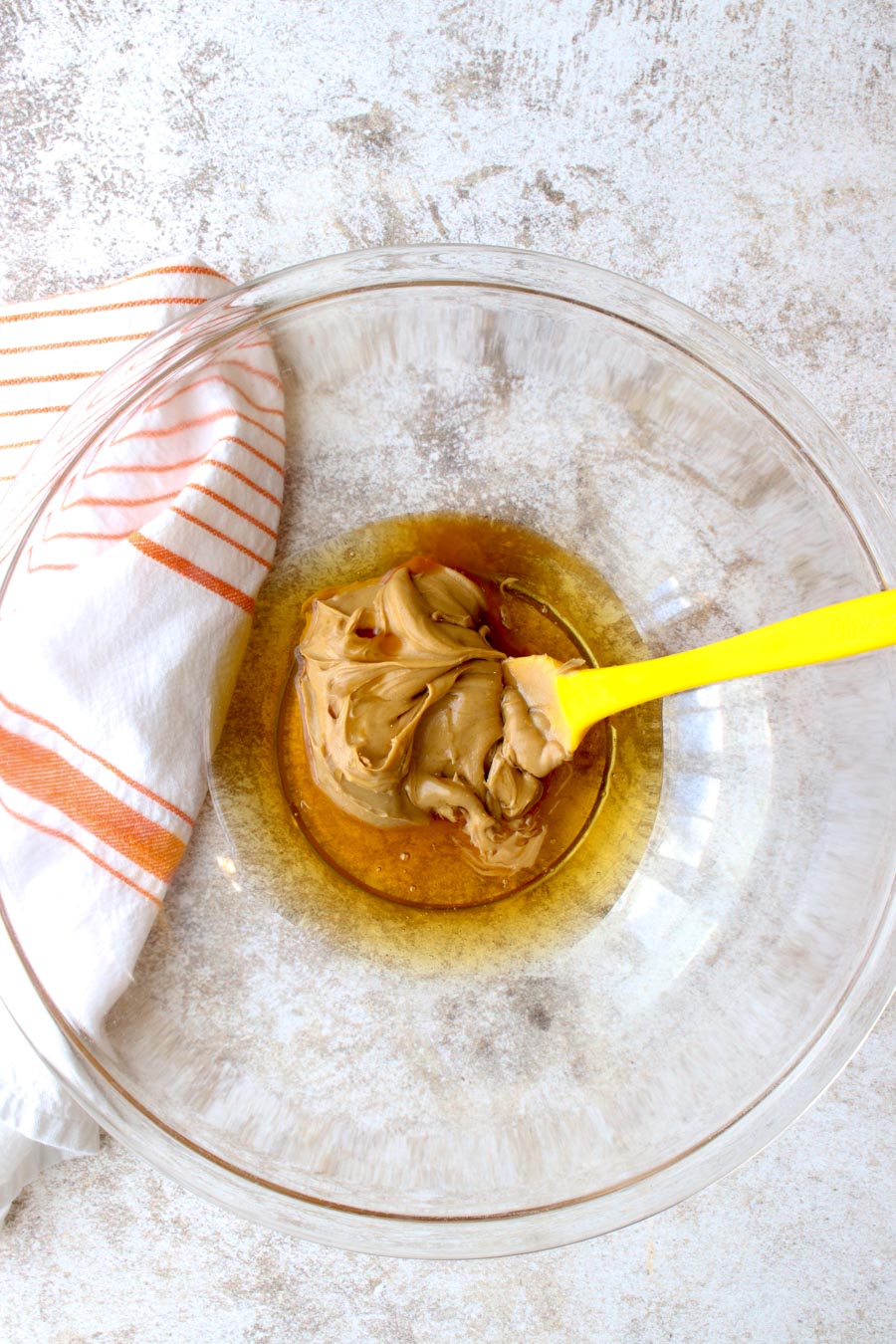 A glass bowl with peanut butter and honey ready to be mixed