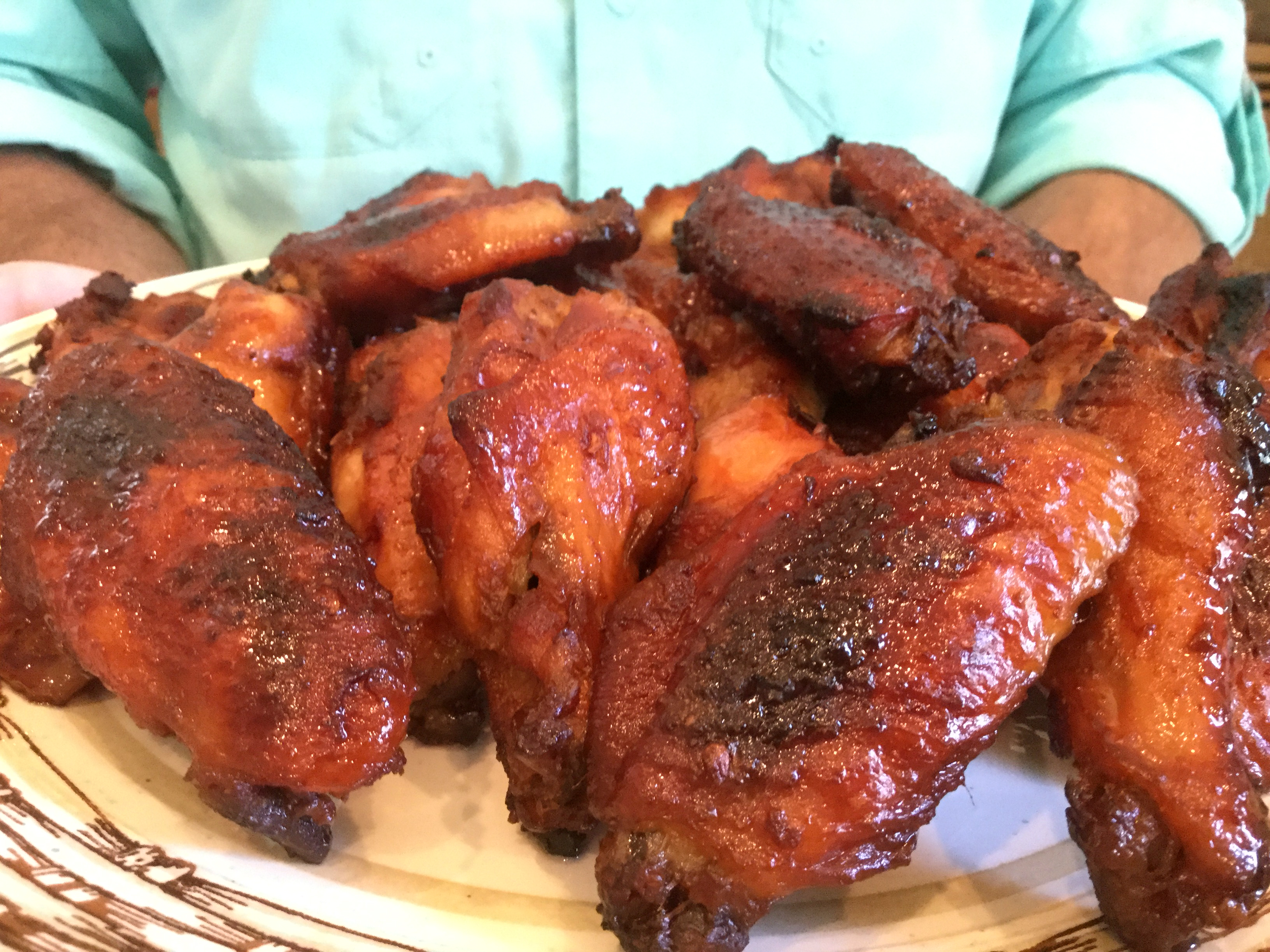 close up man holding plate of cooked wings