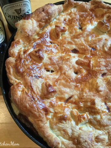 A pie in a skilled with beer bottle in background