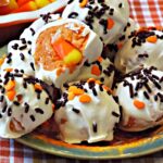 A close up of several cookie balls with sprinkles and a candy corn in center