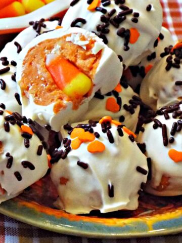 A close up of several cookie balls with sprinkles and a candy corn in center