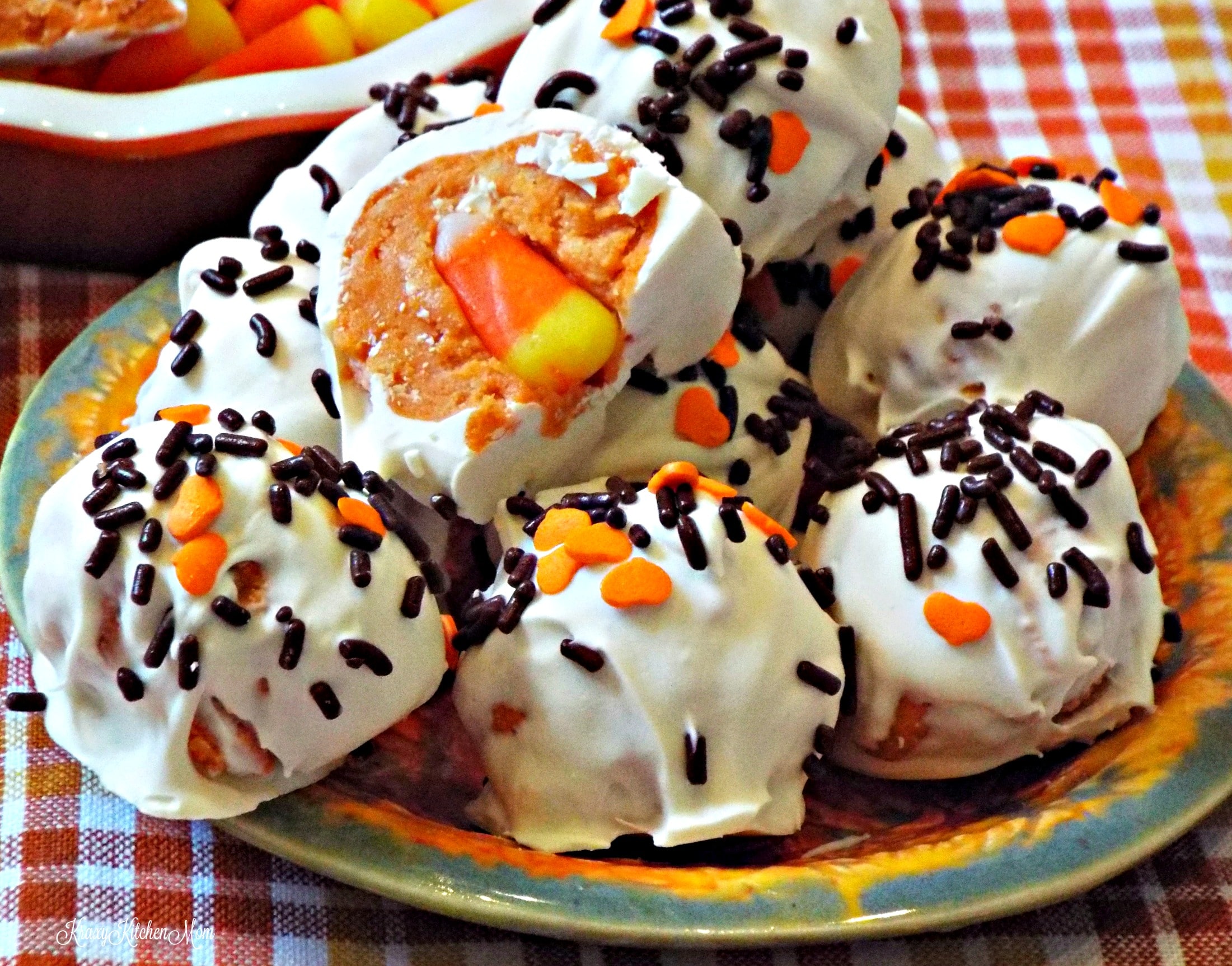 A close up of several cookie balls with sprinkles and a candy corn in center