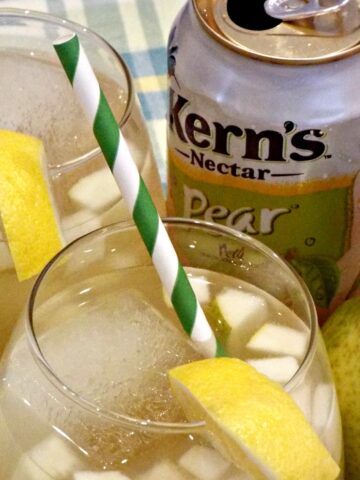 A pear cocktail with a green straw and can in background