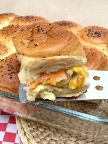 A ham, egg, cheese slide being lifted out of glass pan with a spatula