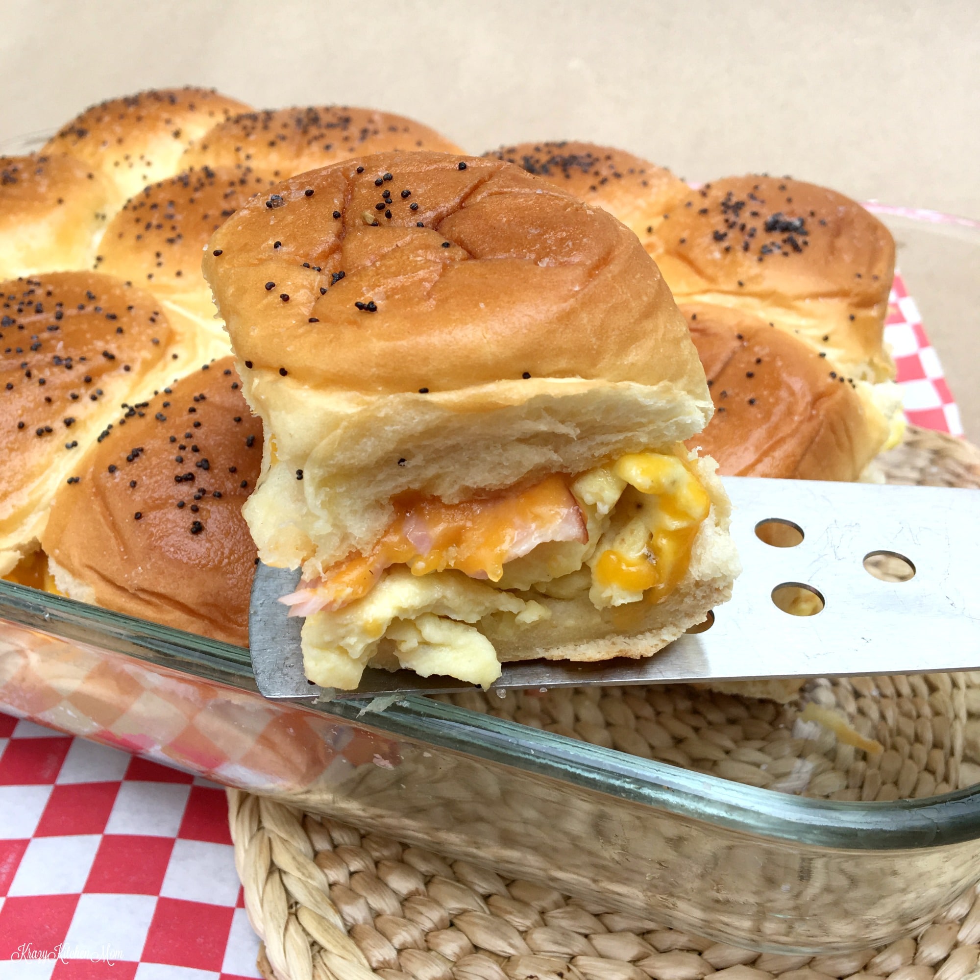 A ham, egg, cheese slide being lifted out of glass pan with a spatula
