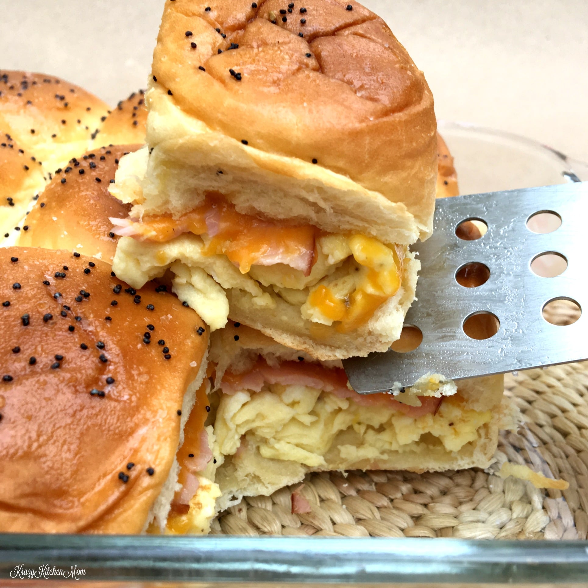 A close up of a ham, cheese, egg slider on a spatula