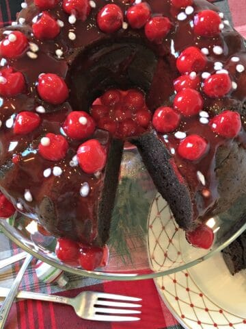 an overhead shot of chocolate cake covered in cherries with forks