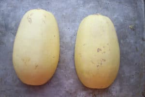 Spaghetti squash cut in half face-side down on pan