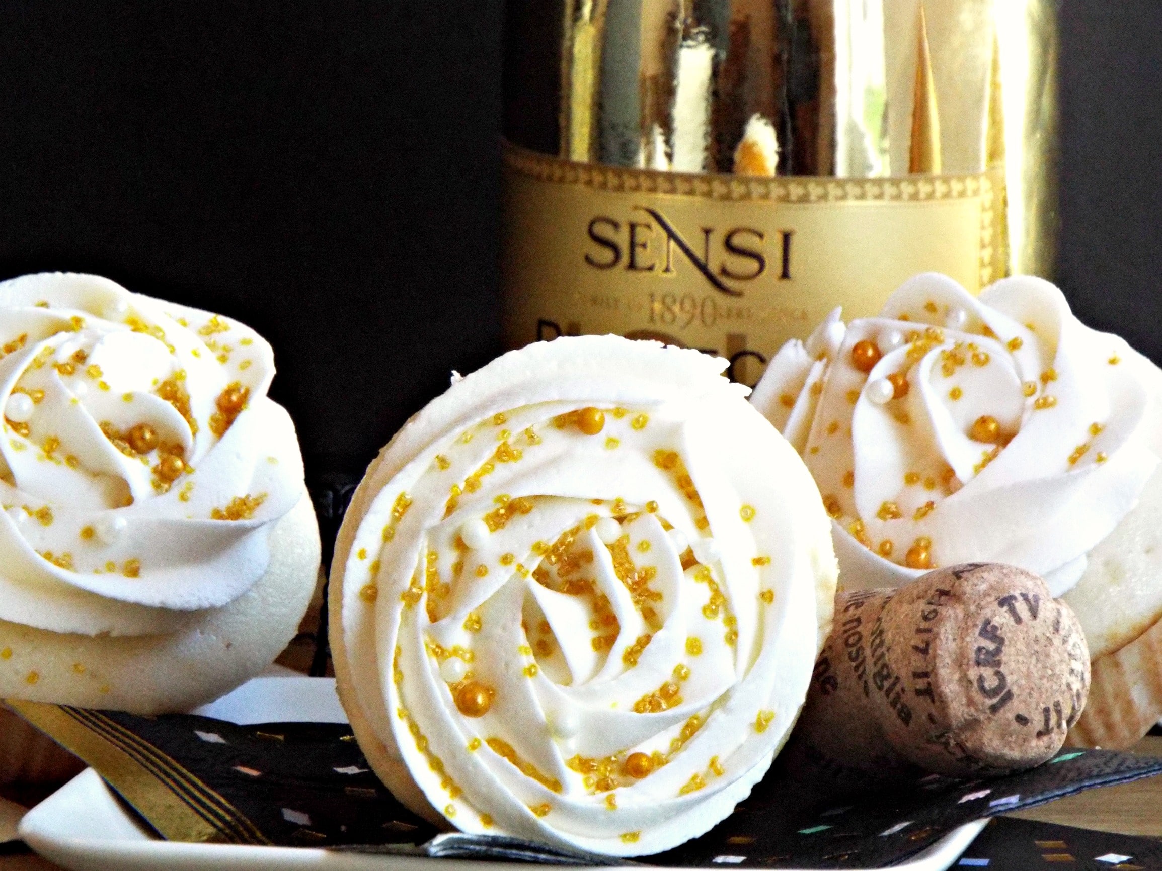 A close up a cupcake on it\'s side with a gold bottle in background