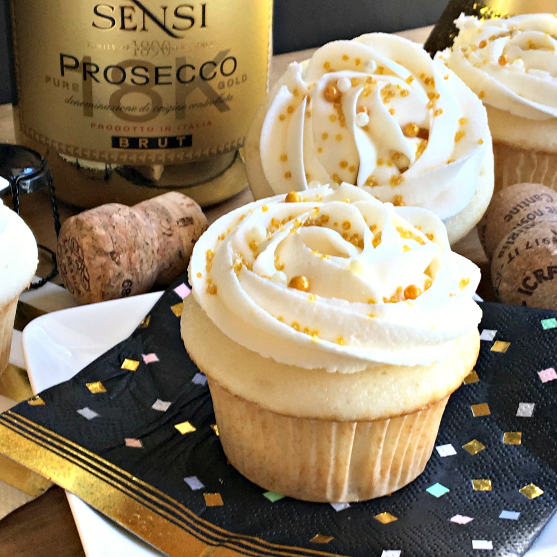 close up of cupcake on a black and gold napkin with gold bottle in background