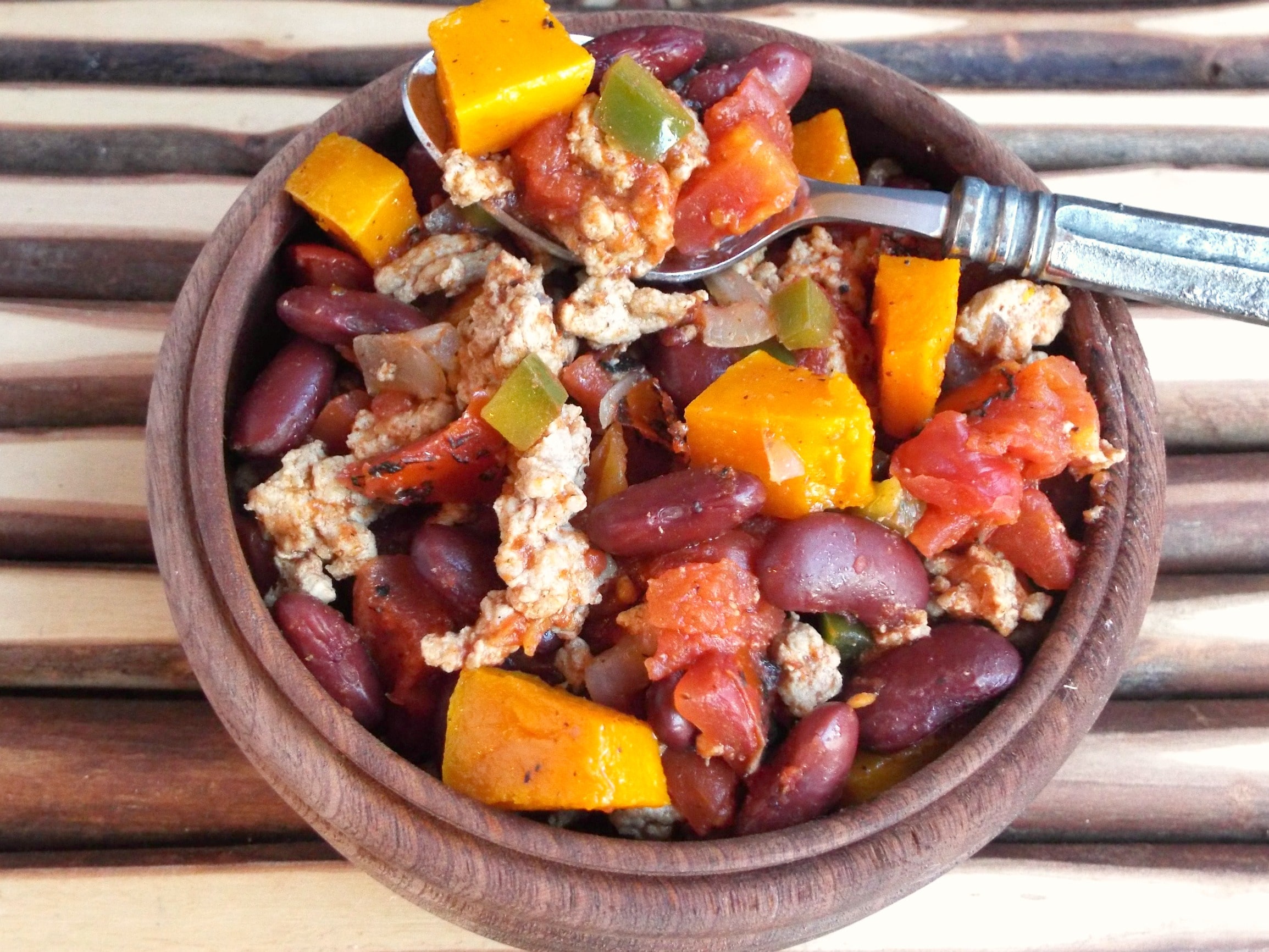 A bowl chili with squash, beans and meat