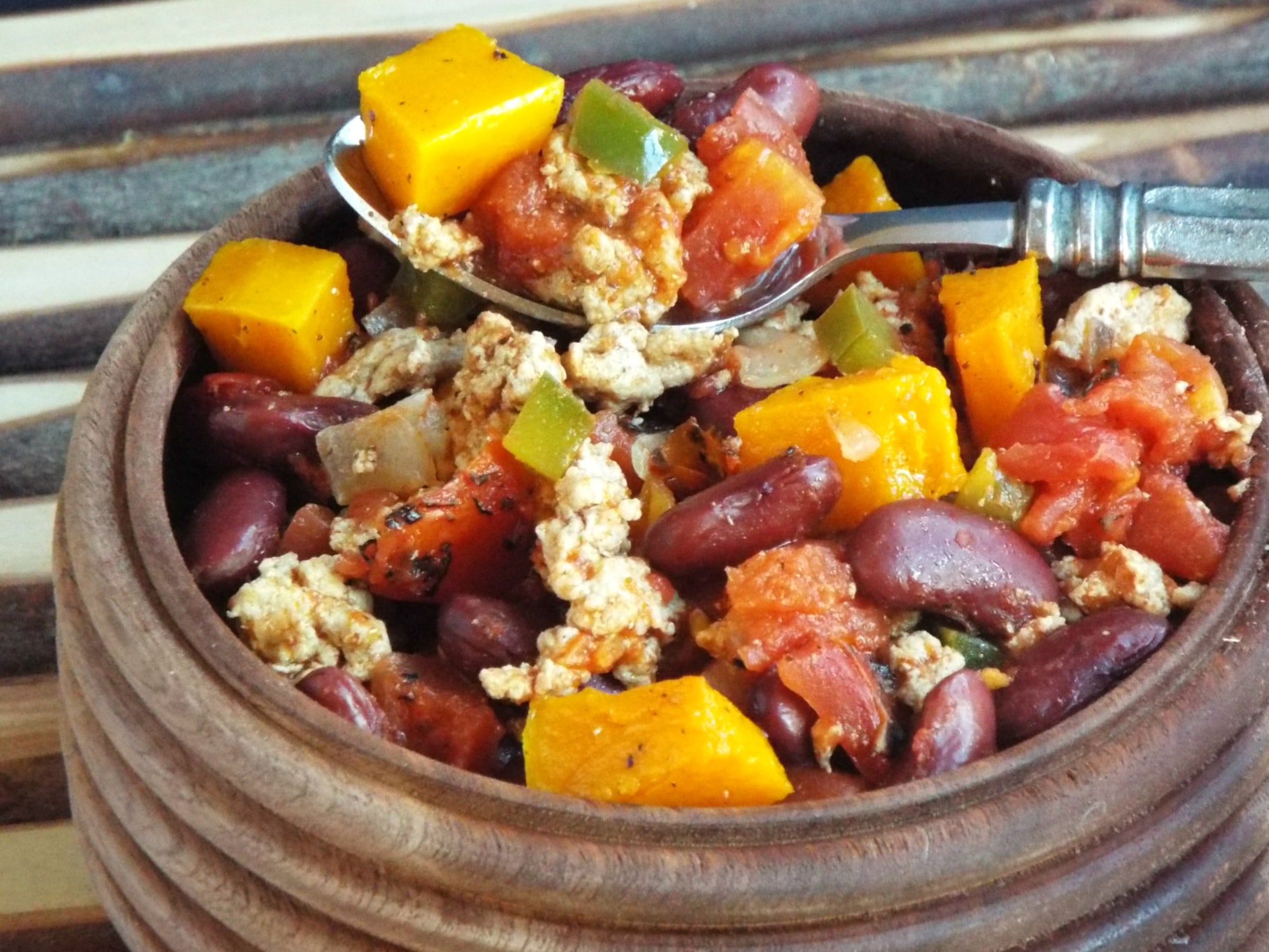 A bowl of chili with squash, beans, and meat