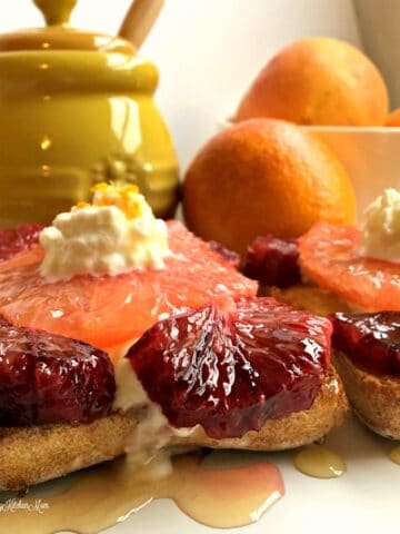 slices of grapefruit and blood oranges topped with whipped cream with yellow jar in background