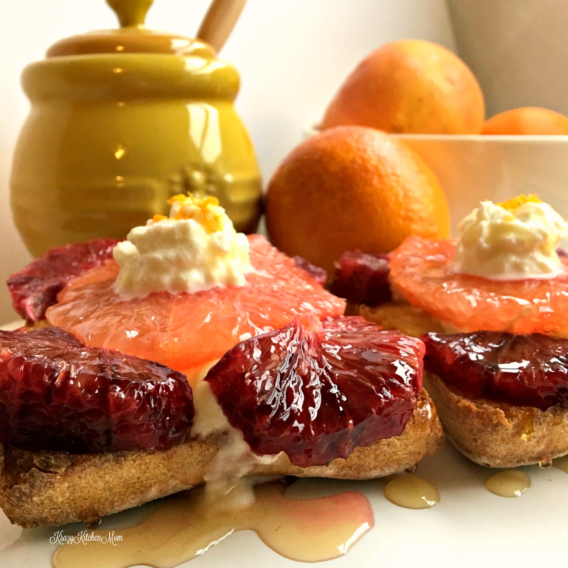 slices of grapefruit and blood oranges topped with whipped cream with yellow jar in background