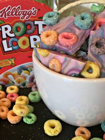 a bowl of candy topped with froot loop cereal with the cereal box in background