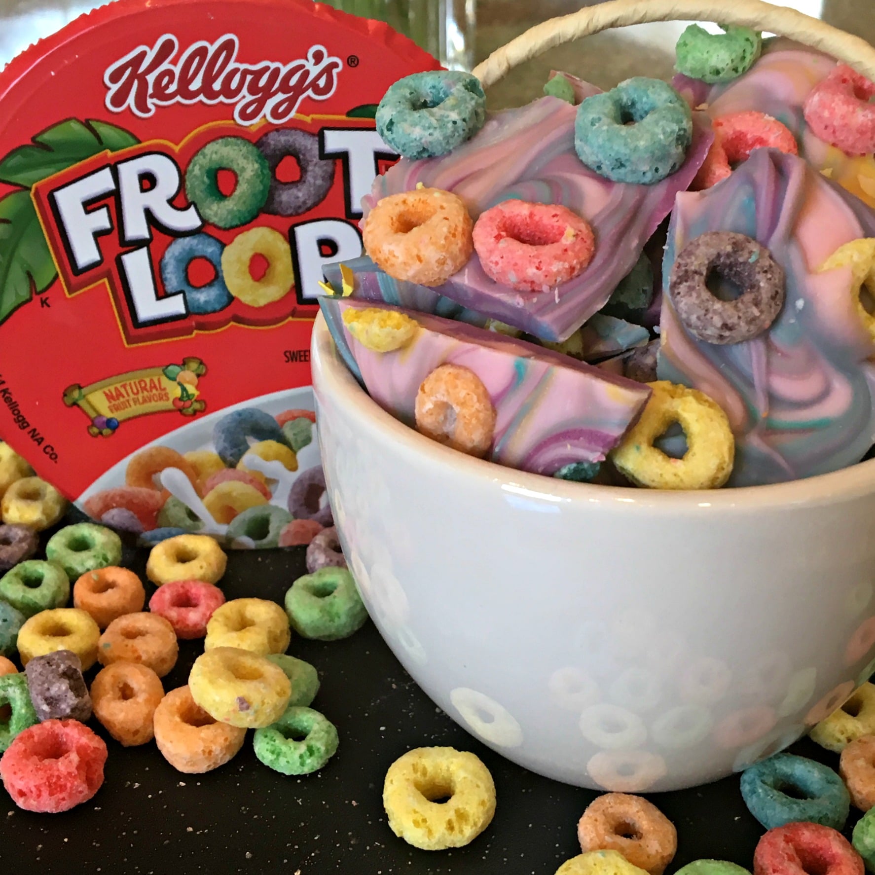 a bowl of candy topped with froot loop cereal with the cereal box in background