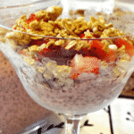 A fancy dish filled with yogurt topped with granola and strawberries