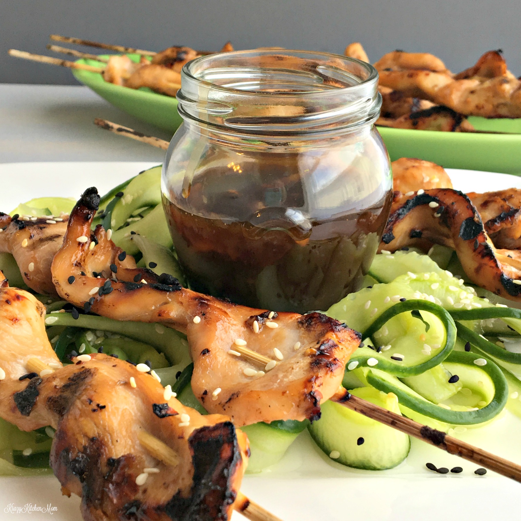 chicken kabobs and cucumber slices with a jar of sauce