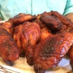 close up man holding plate of cooked wings