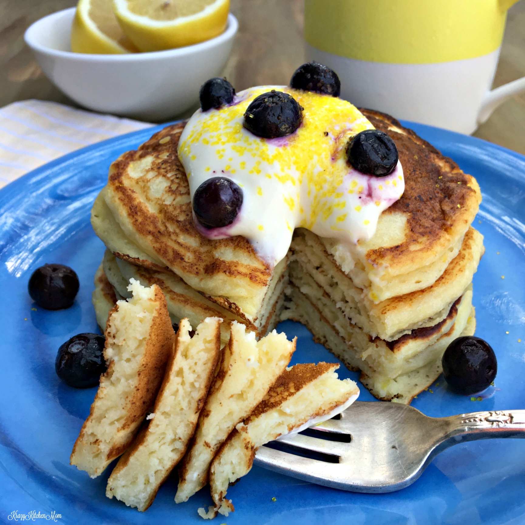 a stack of pancakes with whipped cream and blueberries on top and a fork on a blue plate