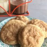 A close up of a plate cookies with chocolate and white milk bottles in background