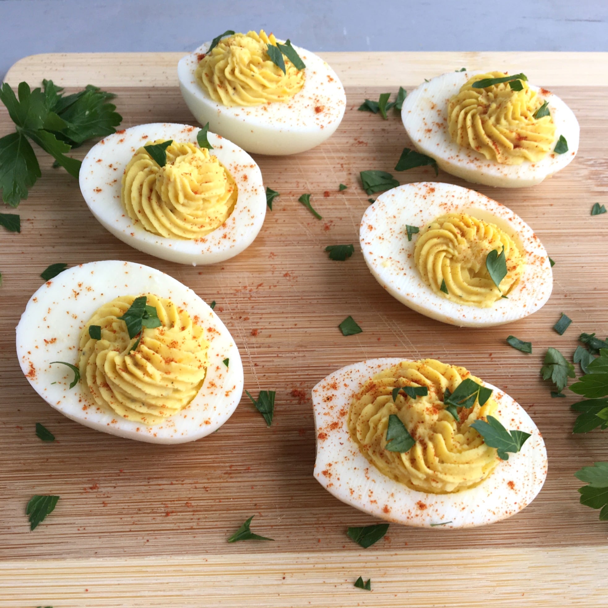 six deviled eggs on a cutting board with parsley
