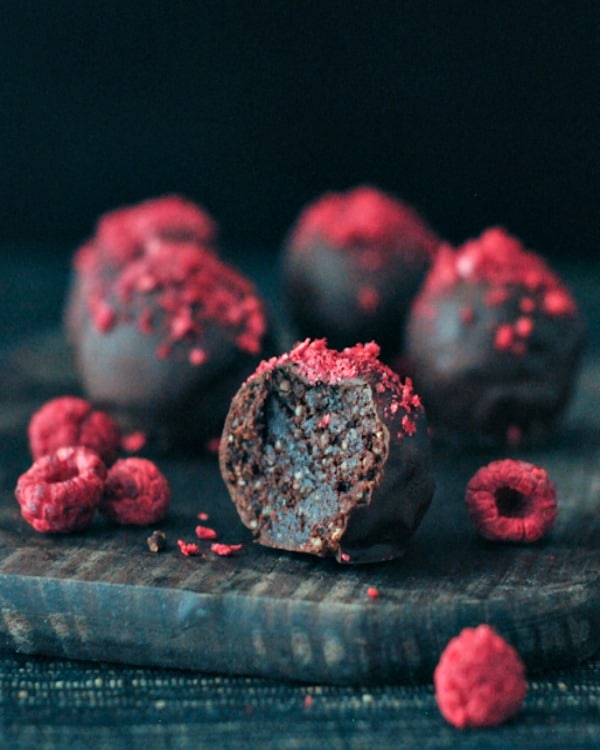 A close up of a dark chocolate truffle candy topped with raspberry dust