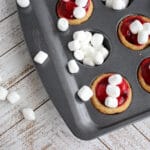 A cupcake tin filled with sugar cookie, cherries and mini marshmallows