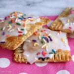 three glazed pop tarts with sprinkles on a pink and white polka dot napkin