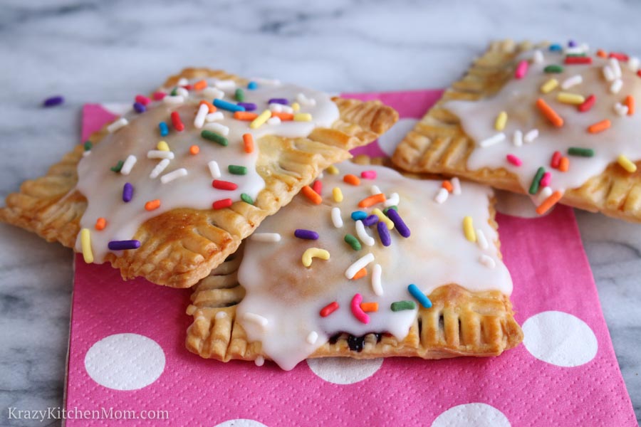 three glazed pop tarts with sprinkles on a pink and white polka dot napkin