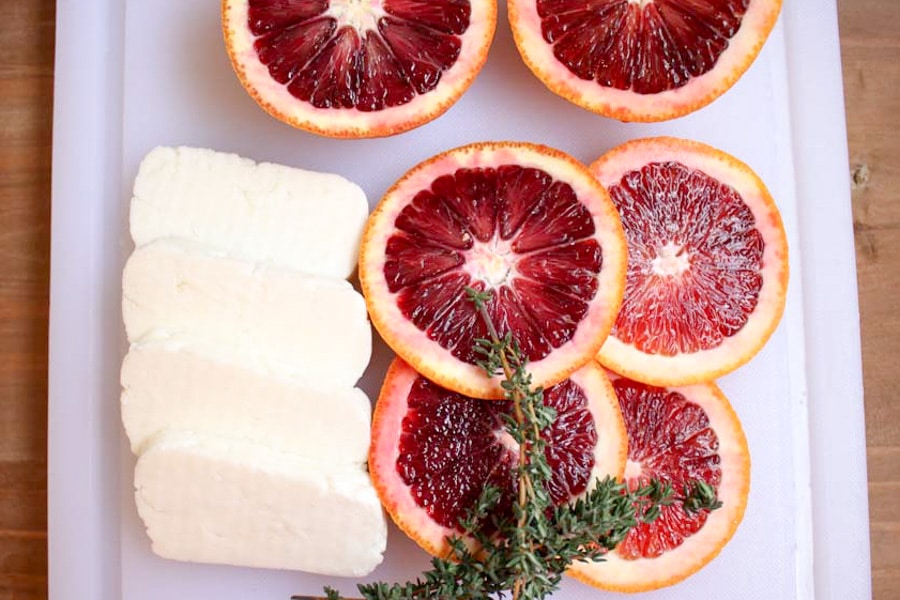 Raw slices of cheese, oranges and herbs ready to cook
