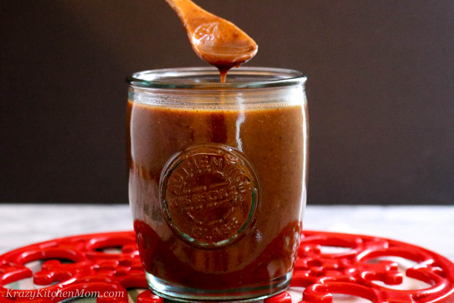 Jar of Enchilada and Sauce with a small wooden spoon dipping into the sauce