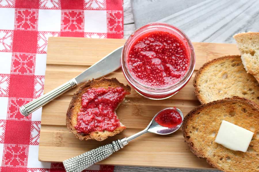 a jar of jam with toast on a cutting board