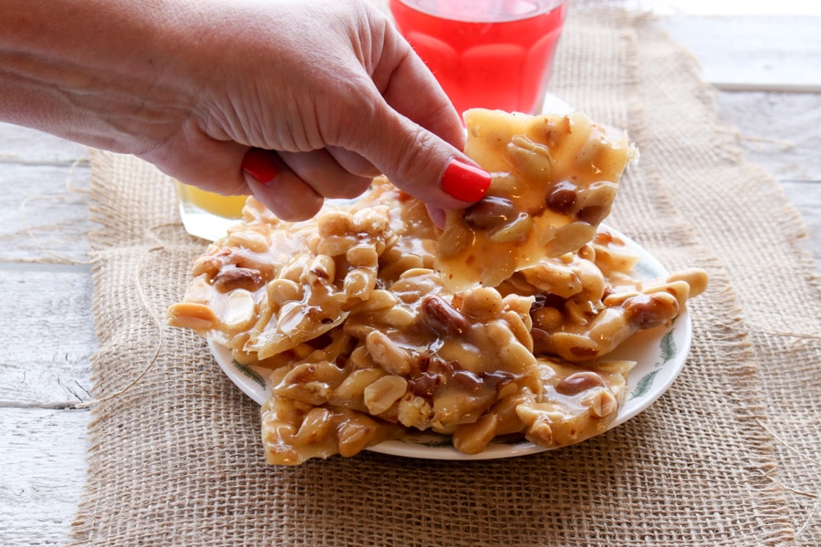 hand picking up a piece of peanut brittle