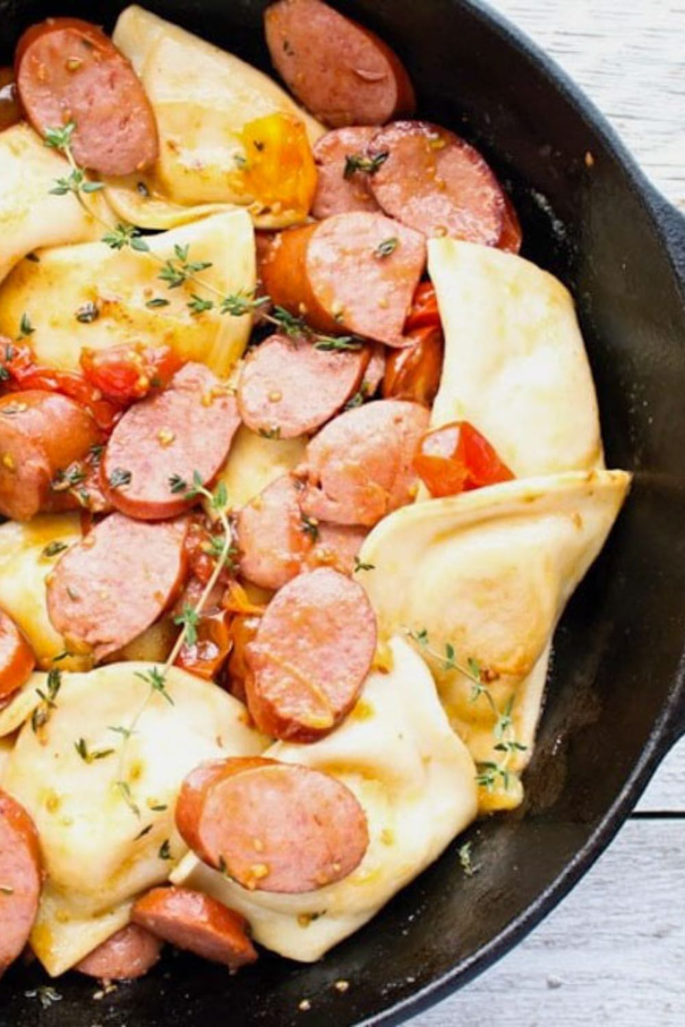 large skillet filled with pierogis and kielbasa