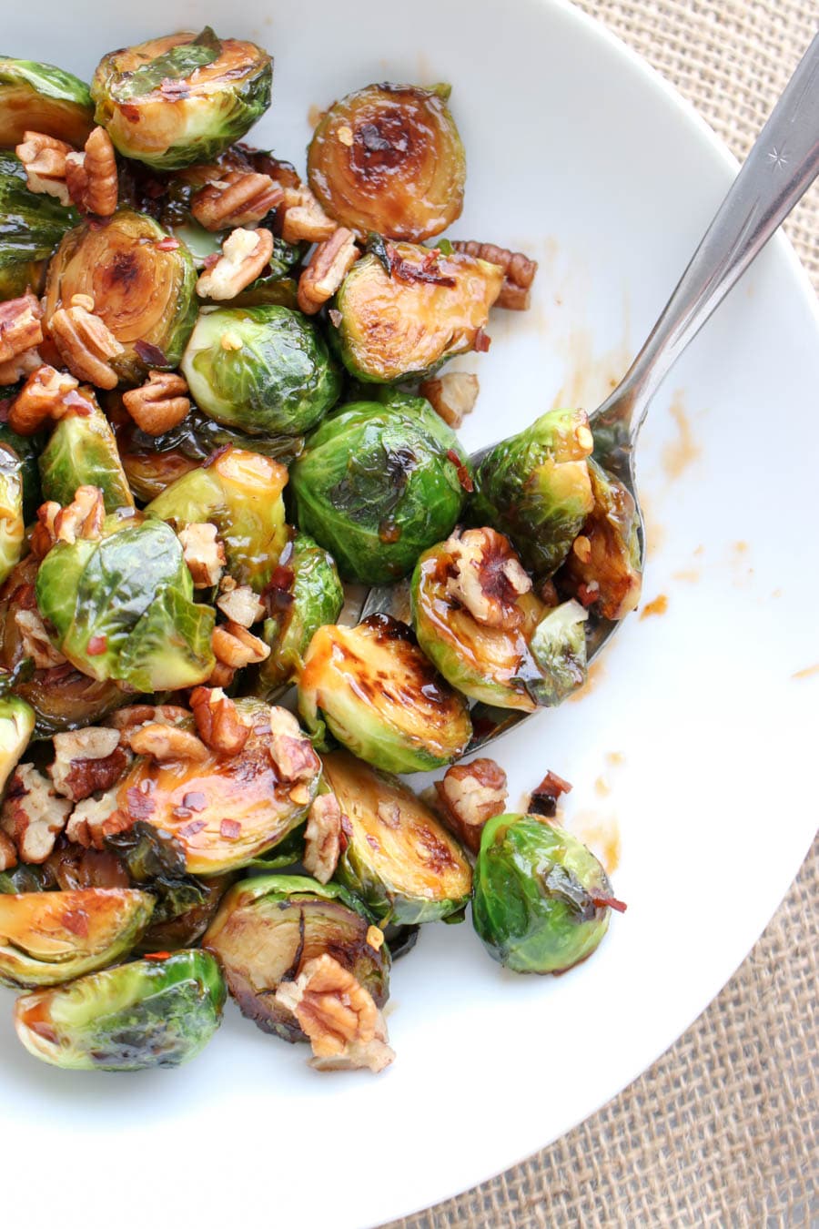 Sweet and Sour Glazed Brussels Sprouts in a serving dish with a spoon