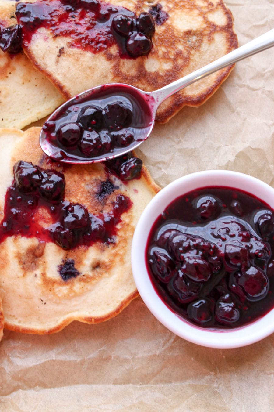 Spoon full of blueberry syrup laying on a pancake