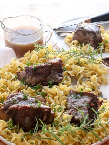 ribs sitting on a plate of noodles