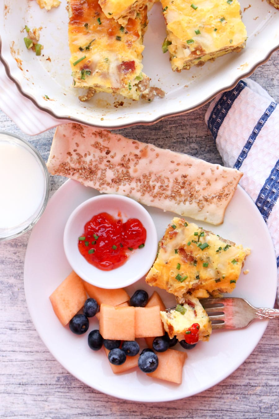 Plate with a piece of casserole, melons and berries, a cracker and hot pepper jelly