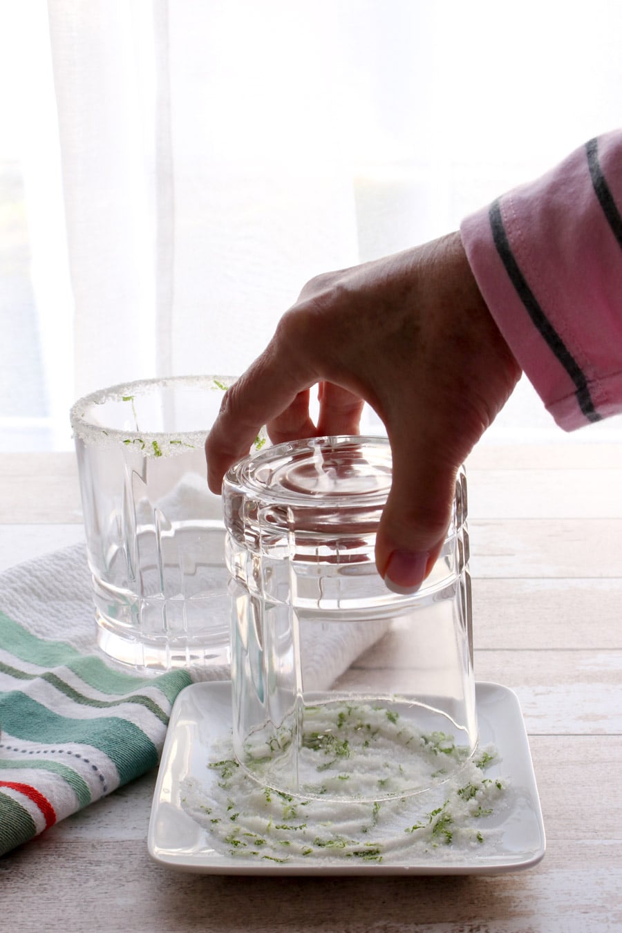 Hand placing rim of glass in salt