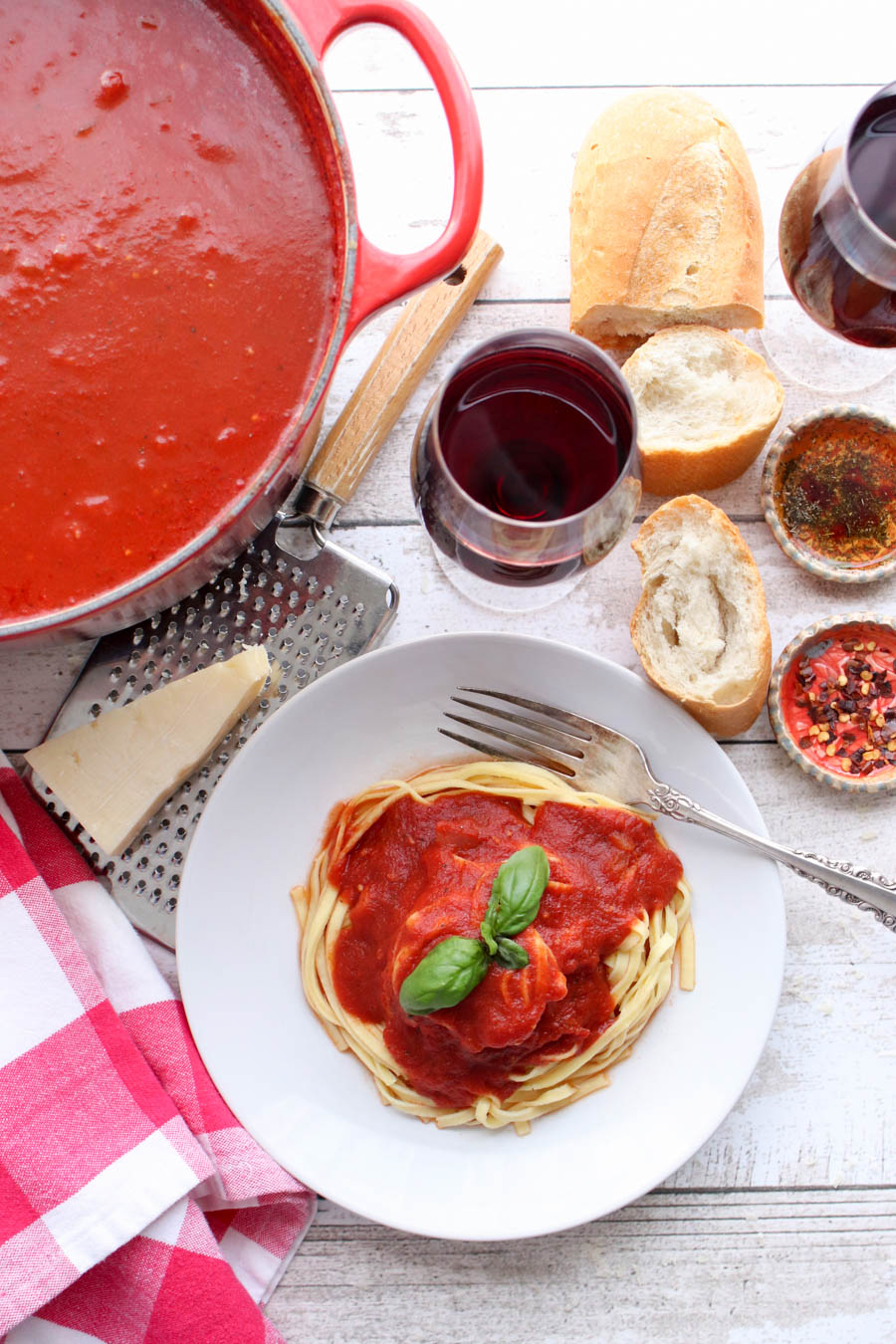 Bowl of pasta, pot of pasta, glass of red wine, bread and cheese