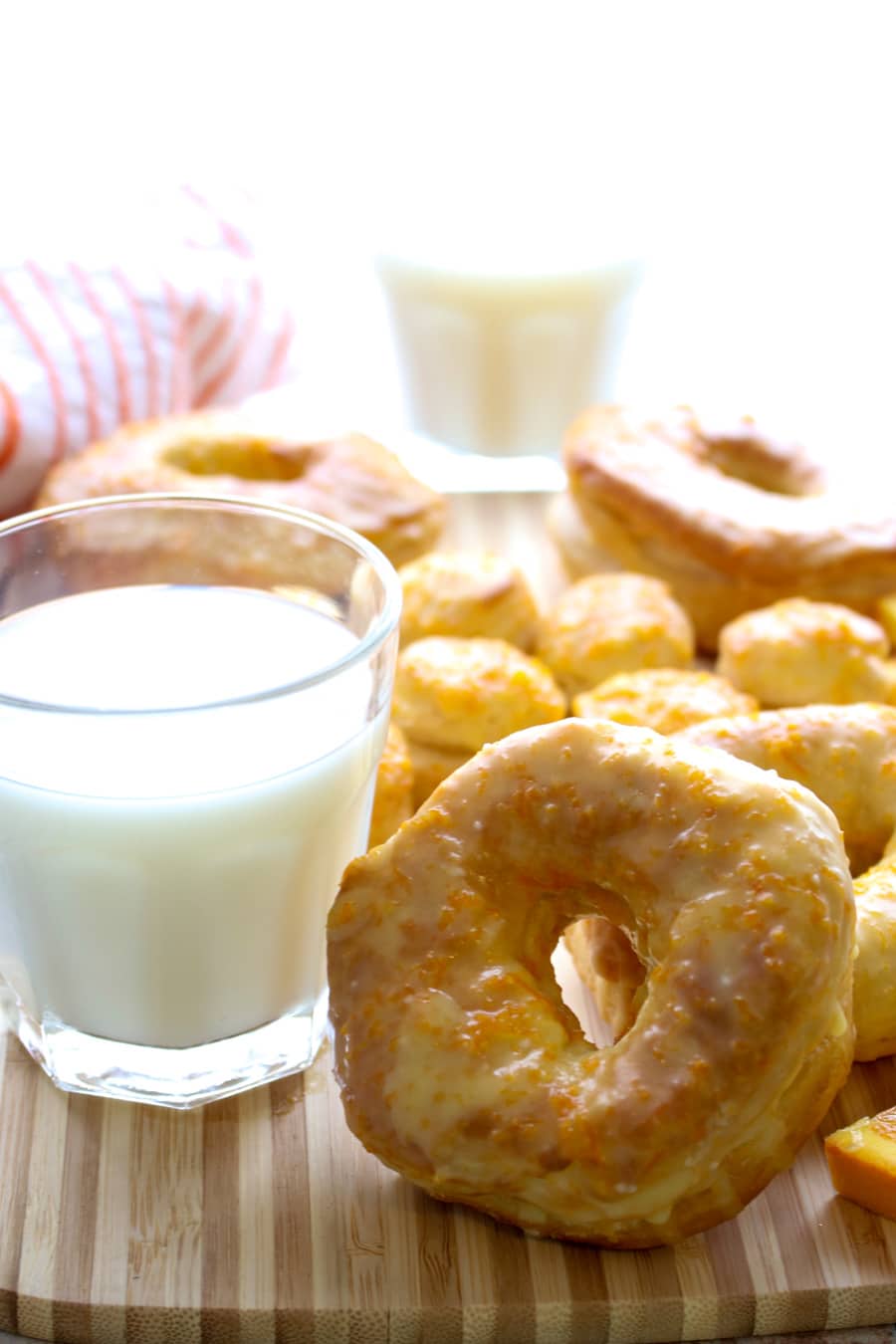 orange glazed donut next to a glass of milk