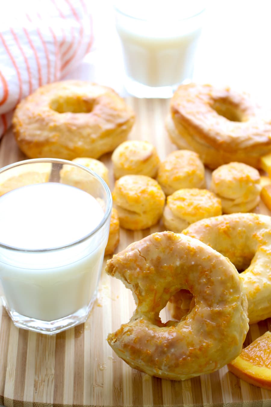 A donut with a bite out leaning against a glass of milk