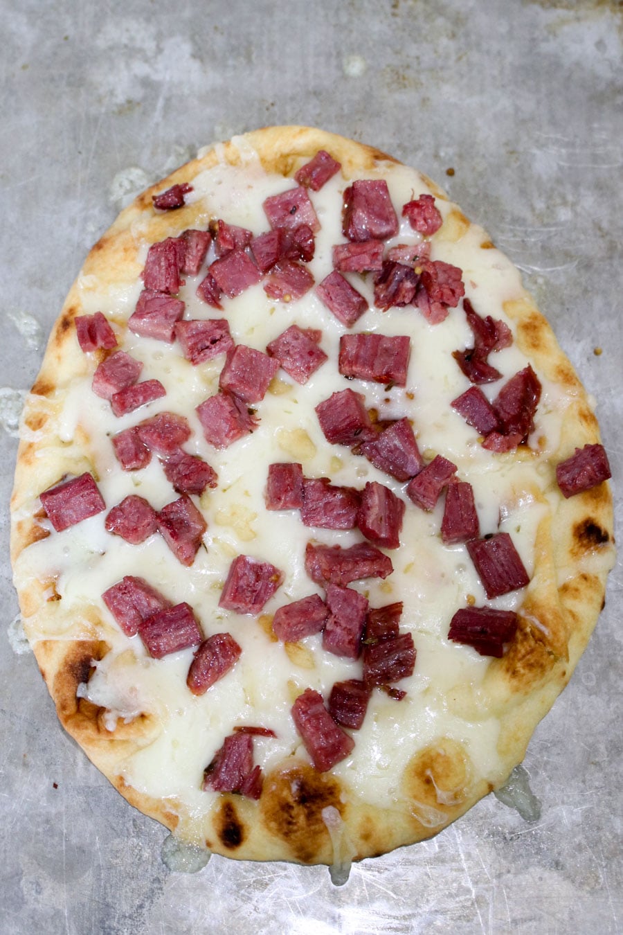 Naan bread covered with Swiss Cheese and corned beef