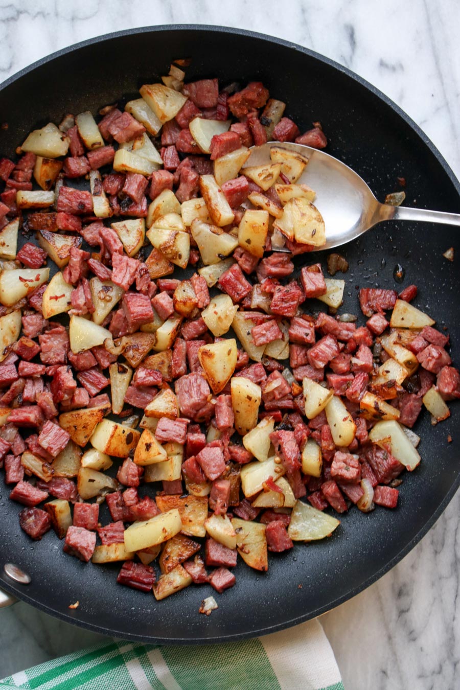 skilled full of corned beef hash with a serving spoon