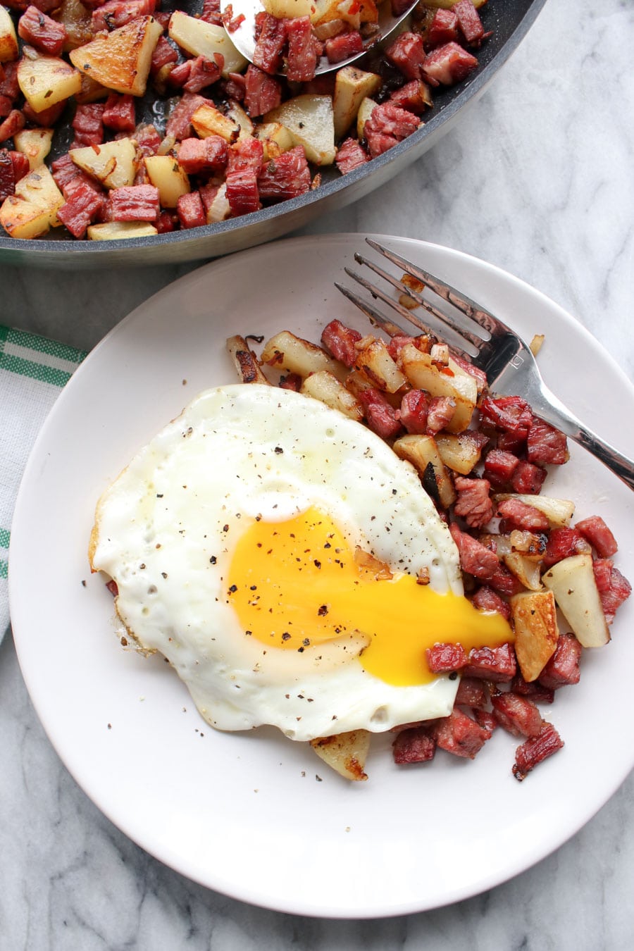 Plate of hash with a broken sunny side up egg on top