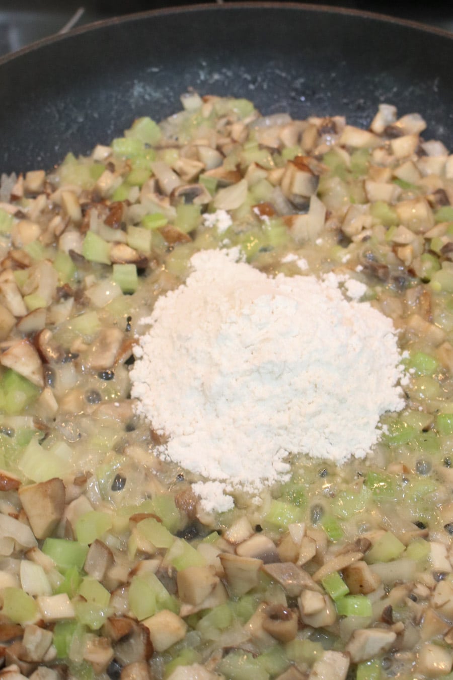 Mushroom, onion, and butter sautéing in a skillet with flour added