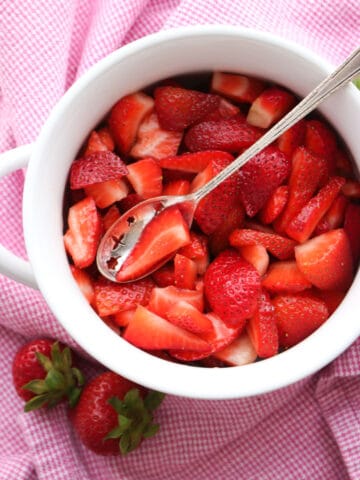 Bowl of bright red strawberries with a spoon