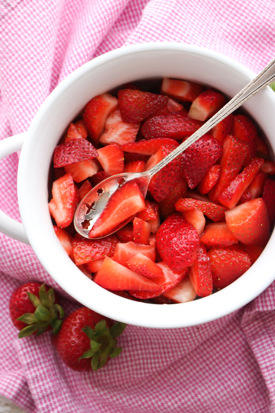 Bowl of bright red strawberries with a spoon