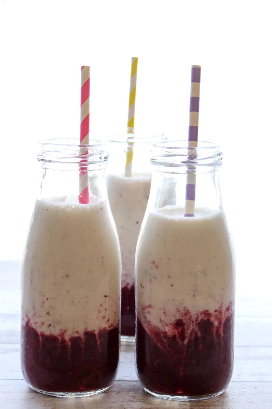 THREE BOTTLES OF BANANA BERRY YOGURT SMOOTHIES WITH COLORFUL STRAWS